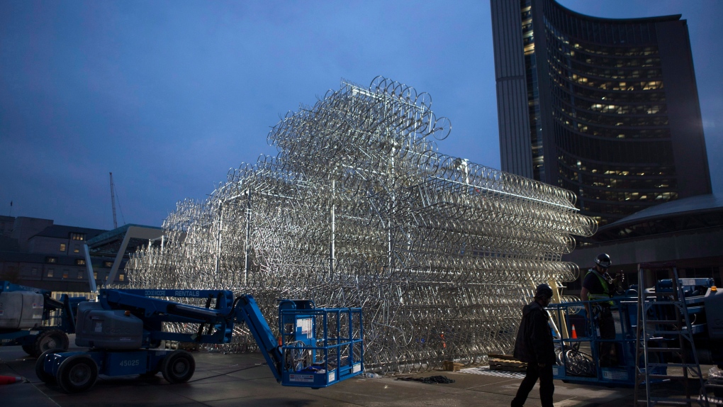 A worker walks past the partially-built part of Chinese artist Ai Weiwei's Forever Bicycles sculpture in front of Toronto's City Hall on Monday, Sept. 30, 2013. (The Canadian Press/Chris Young)