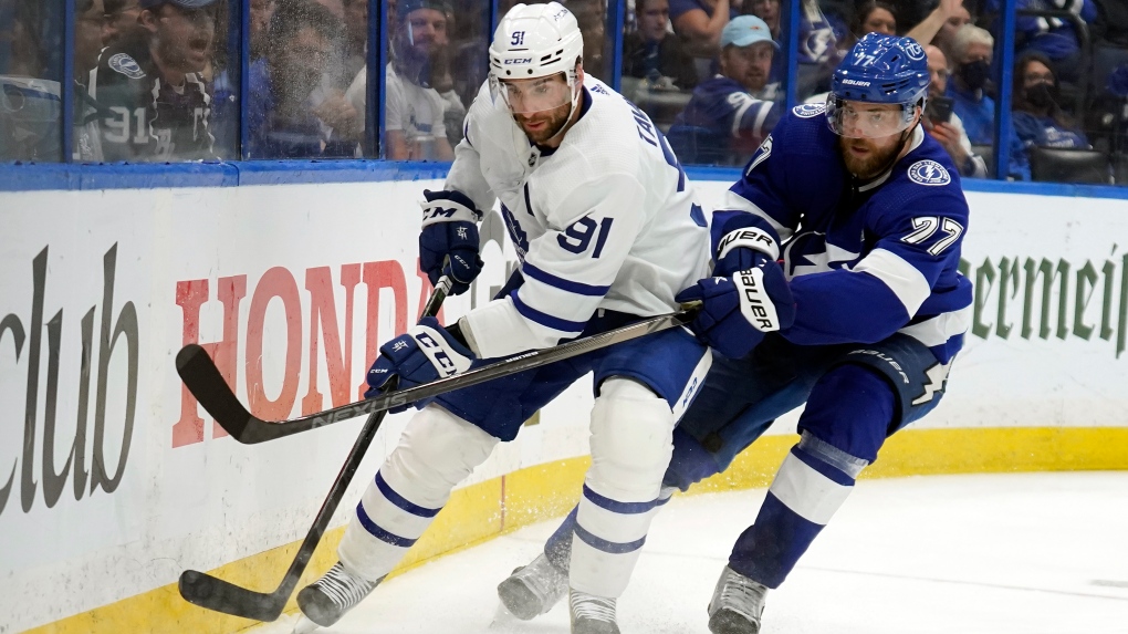 Toronto Maple Leafs center John Tavares (91) plays the puck from his knees in front of Tampa Bay Lightning center Brayden Point (21) during the third period in Game 6 of an NHL hockey first-round playoff series Thursday, May 12, 2022, in Tampa, Fla. (AP Photo/Chris O'Meara)