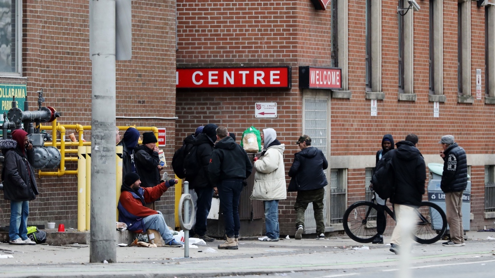 Men gather outside of a shelter in downtown Toronto on Saturday, March 28, 2020. THE CANADIAN PRESS/Colin Perkel