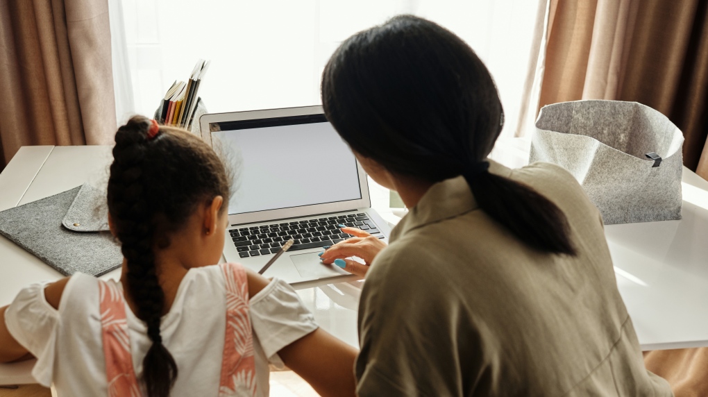 Mother and daughter sit in front of a blank computer screen. (August de Richelieu/Pexels)