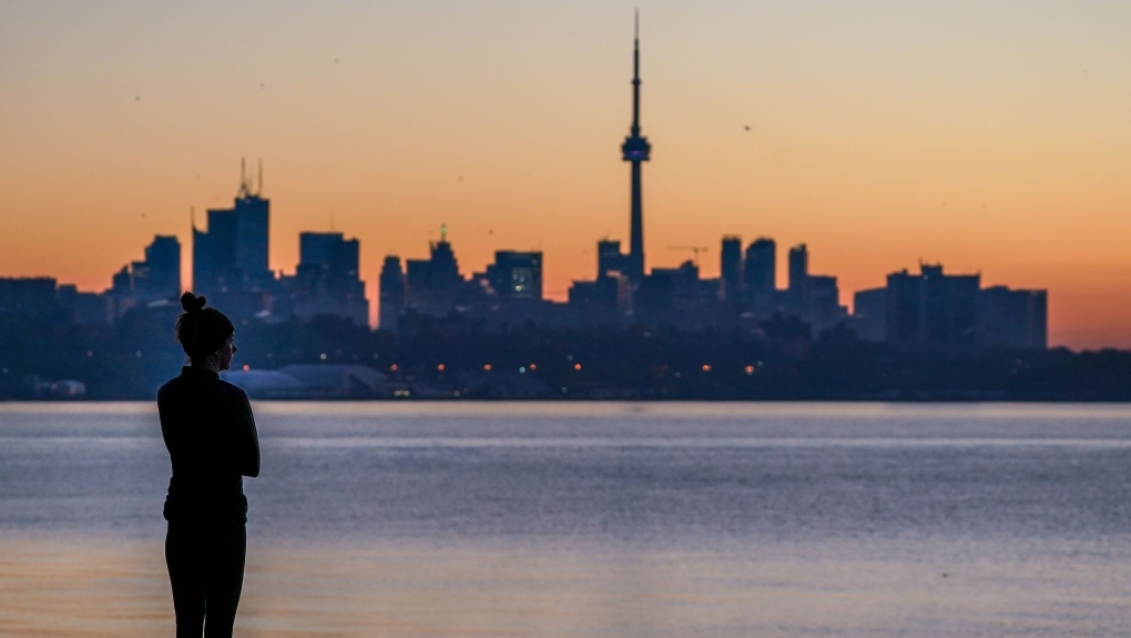 A woman looks out at the Toronto skyline from Sheldon Lookout during sunrise in Toronto on Friday, November 5, 2021. THE CANADIAN PRESS/Evan Buhler 
