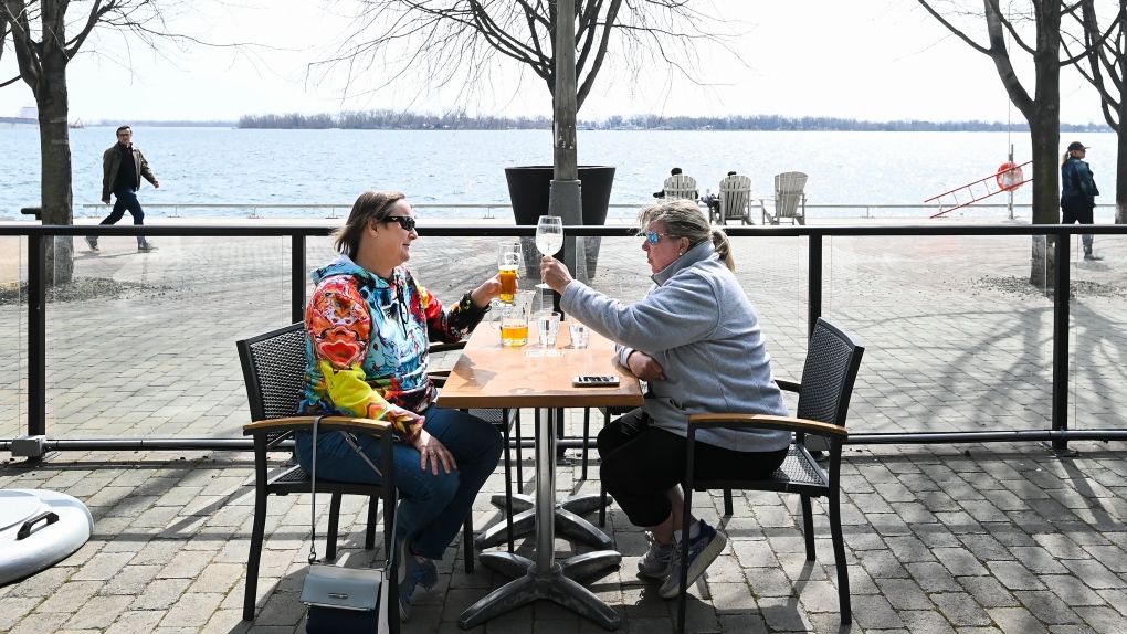 Diana Blaikie, left, and Bonnie Ryder have a cocktail on a outdoor patio at the Grain Urban Tavern while enjoying the warm weather along the boardwalk during the COVID-19 pandemic in Toronto on Thursday, March 25, 2021. THE CANADIAN PRESS/Nathan Denette
