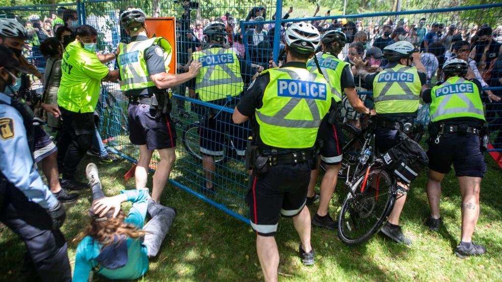 Police try to hold back protesters as they break through a fence during an eviction process at a homeless encampment in Toronto on Tuesday, June 22, 2021. THE CANADIAN PRESS/Chris Young