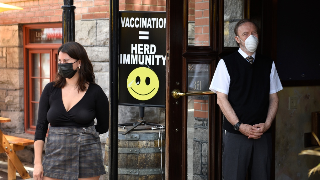 A sign encouraging vaccination is seen at the doors of a pub as staff watch patrons arrive, in Ottawa on the first day of Ontario's first phase of re-opening amidst the third wave of the COVID-19 pandemic, on Friday, June 11, 2021. THE CANADIAN PRESS/Justin Tang 