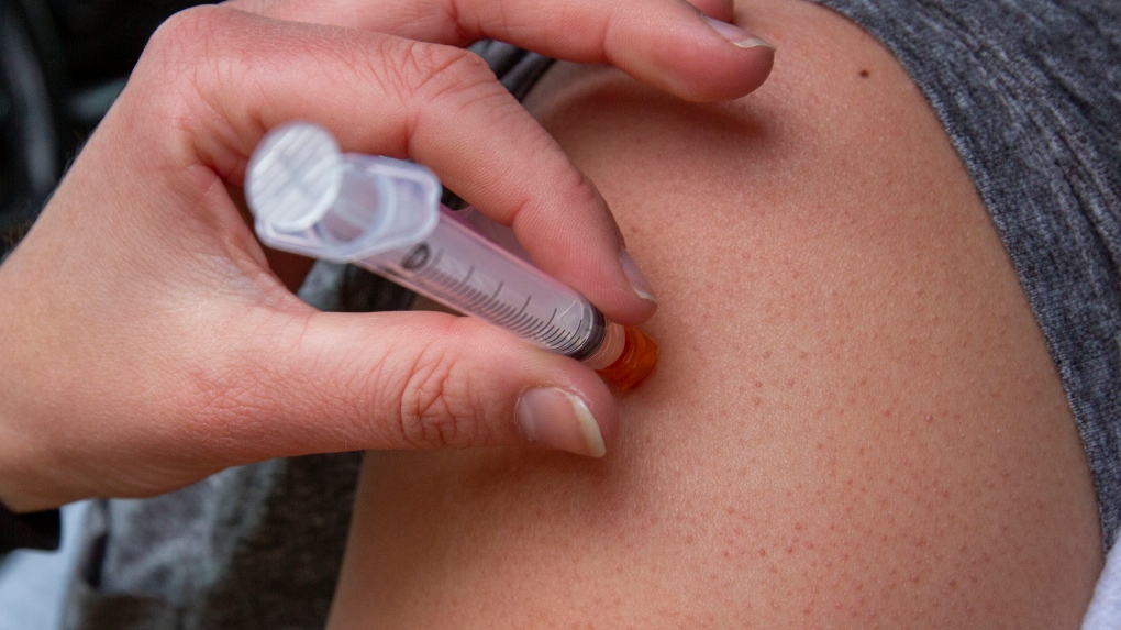 A person receives a COVID-19 vaccine at a drive-thru clinic at Richardson Stadium in Kingston, Ont., on Friday, May 28, 2021. THE CANADIAN PRESS/Lars Hagberg 