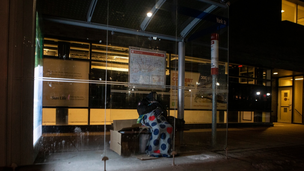 A homeless man sleeps in a bus shelter, in Toronto, on Friday, March 11, 2022. THE CANADIAN PRESS/Chris Young