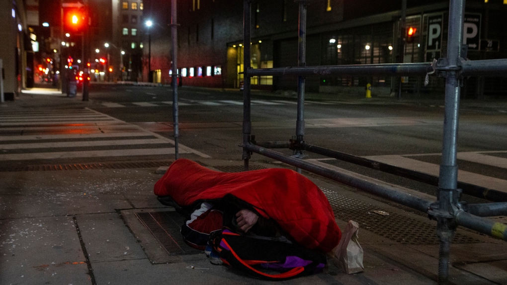 A homeless man sleeps on the street, in Toronto, on Friday, March 11, 2022. THE CANADIAN PRESS/Chris Young