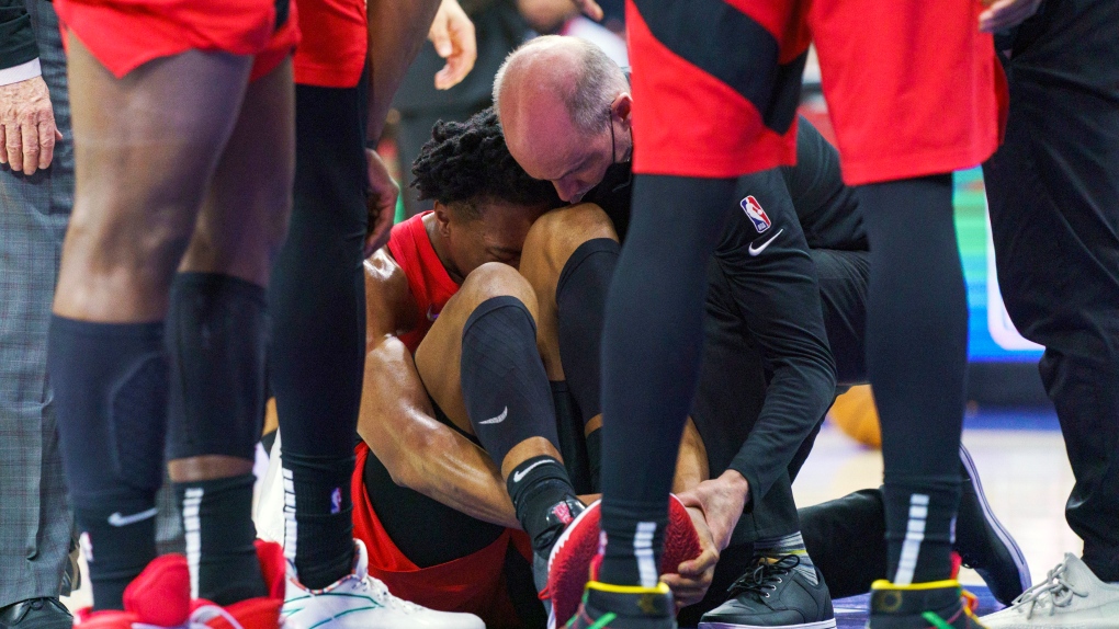 Toronto Raptors' Scottie Barnes, center, gets looked over by the training staff after injuring his left leg during the second half of Game 1 of an NBA basketball first-round playoff series against the Philadelphia 76ers, Saturday, April 16, 2022, in Philadelphia. The 76ers won 131-111. (AP Photo/Chris Szagola)