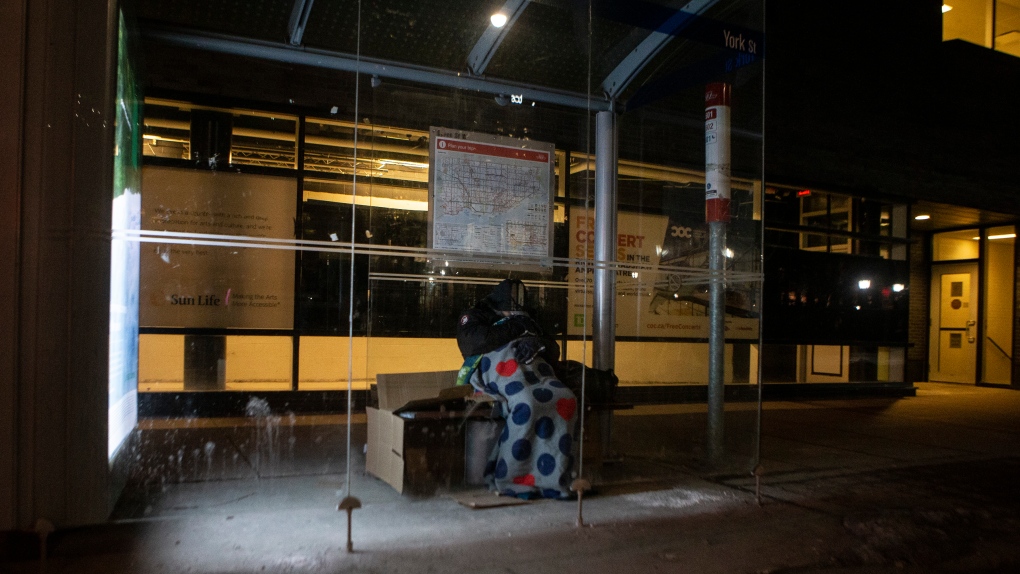 A homeless man sleeps in a bus shelter, in Toronto, on Friday, March 11, 2022. THE CANADIAN PRESS/Chris Young