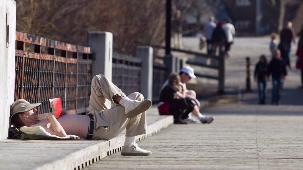 A man reads a book and enjoys the sunshine on a bridge at Cedarvale Park in Toronto in March 2012. THE CANADIAN PRESS/Pawel Dwulit